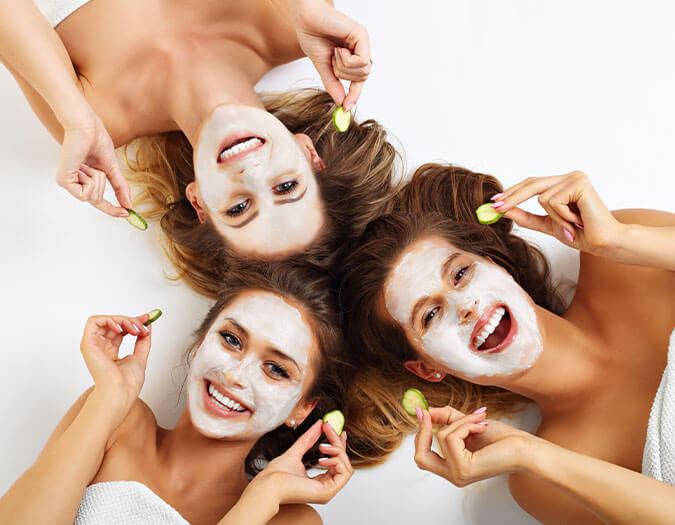 Three girls smiling with face masks applied to skin