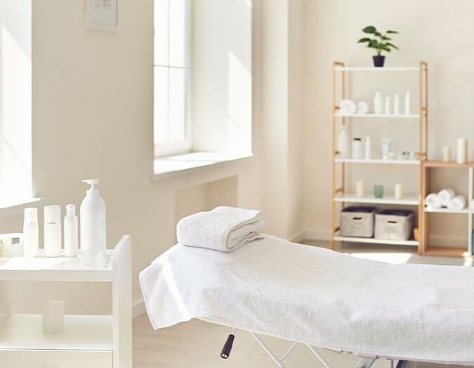 White and cozy spa room with a table in the middle and products on display