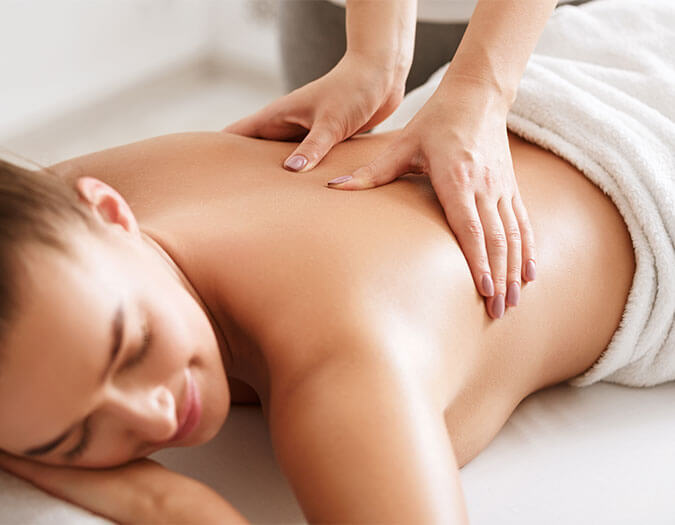 Woman lying on a bed, having a therapeutic massage on her back